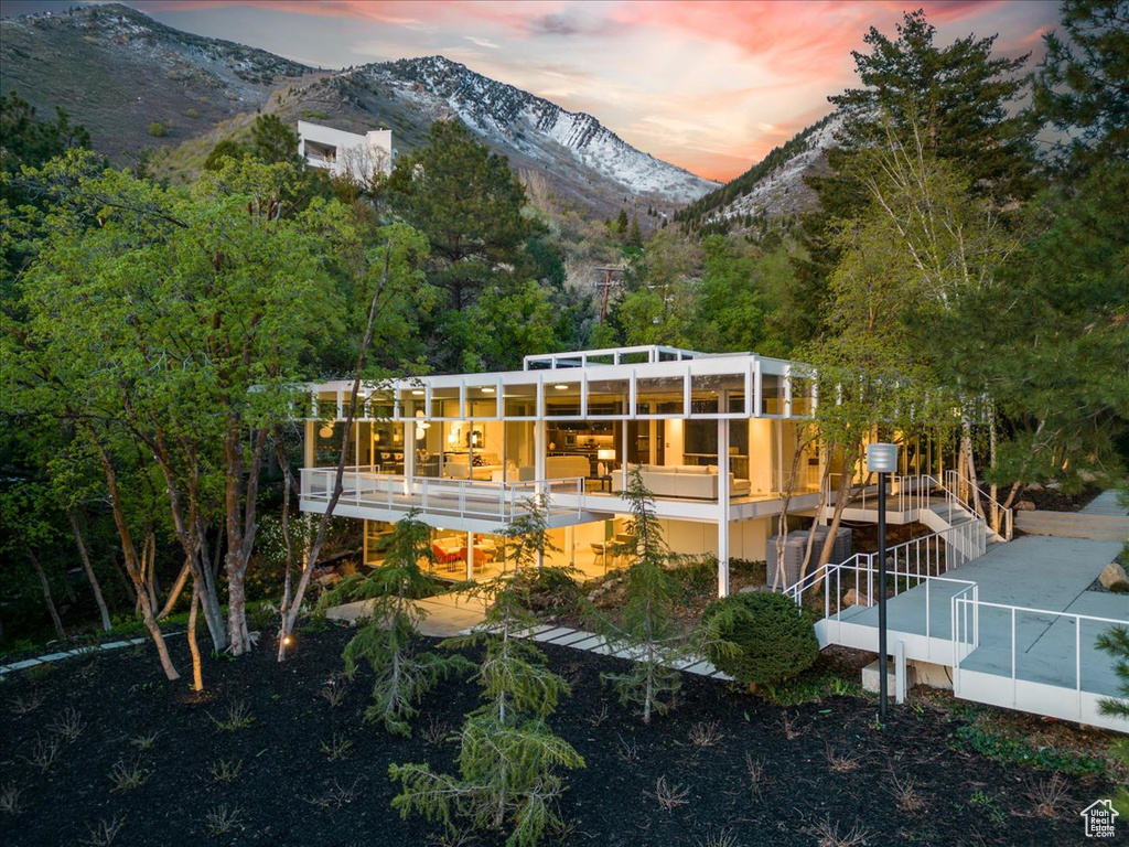 Back house at dusk with a deck with mountain view