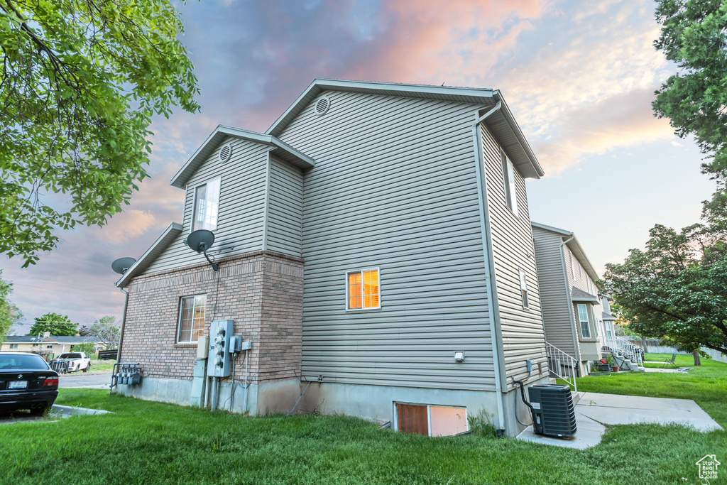 Property exterior at dusk featuring central AC and a lawn