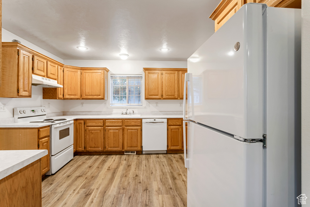 Kitchen featuring sink, white appliances, and light wood-type flooring