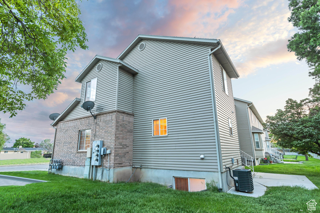 Property exterior at dusk featuring central AC and a lawn