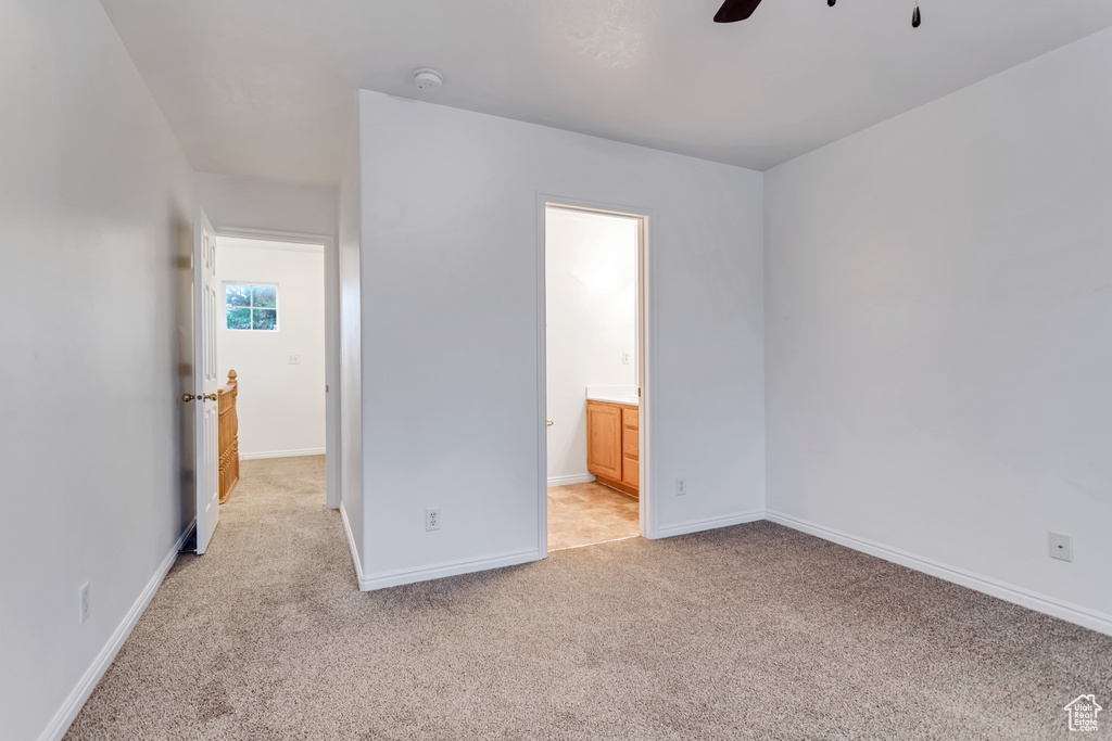 Unfurnished bedroom featuring ceiling fan, light colored carpet, and ensuite bathroom