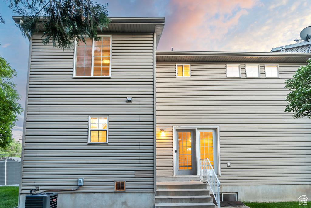 Back house at dusk featuring central air condition unit