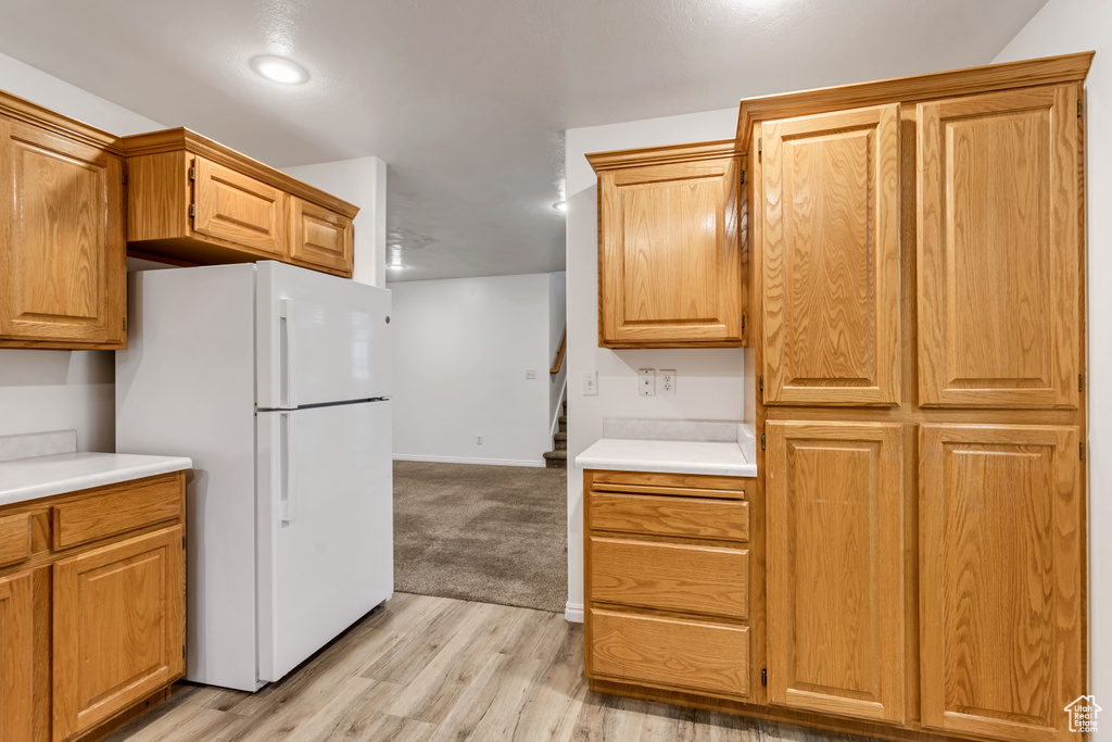 Kitchen with white refrigerator and light colored carpet