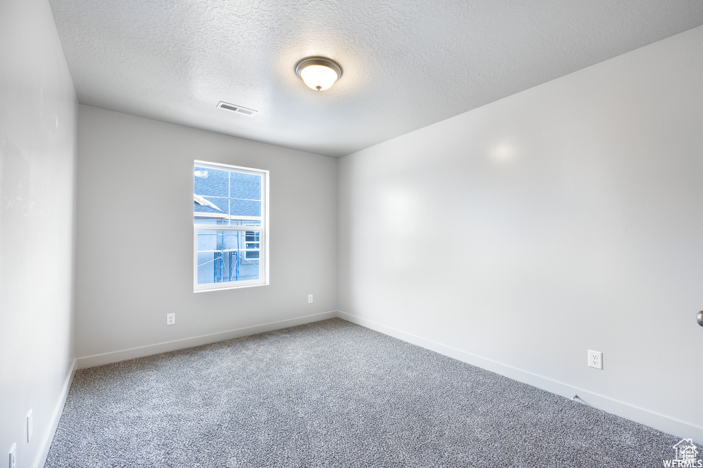 Carpeted empty room featuring a textured ceiling