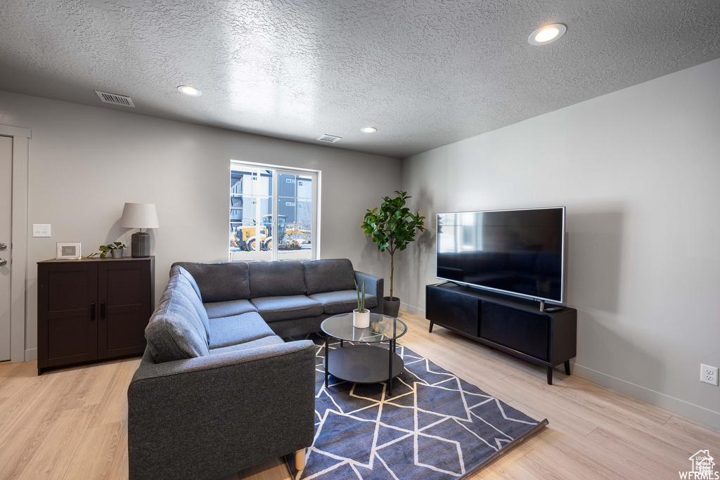 Living room with light hardwood / wood-style floors and a textured ceiling