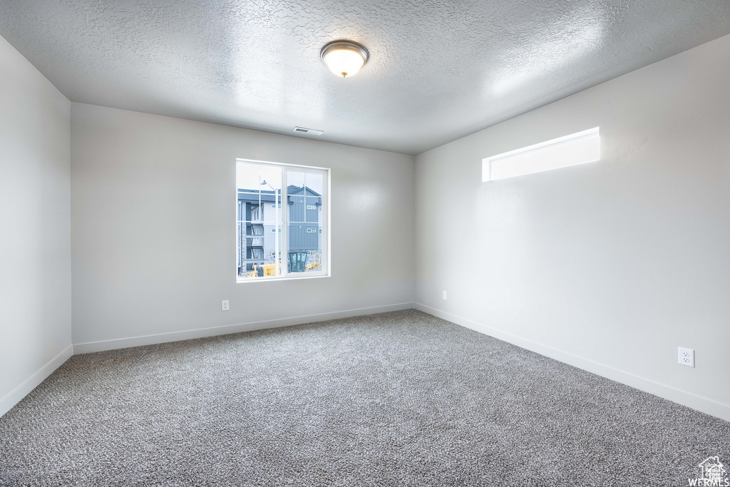 Empty room featuring a textured ceiling and carpet flooring