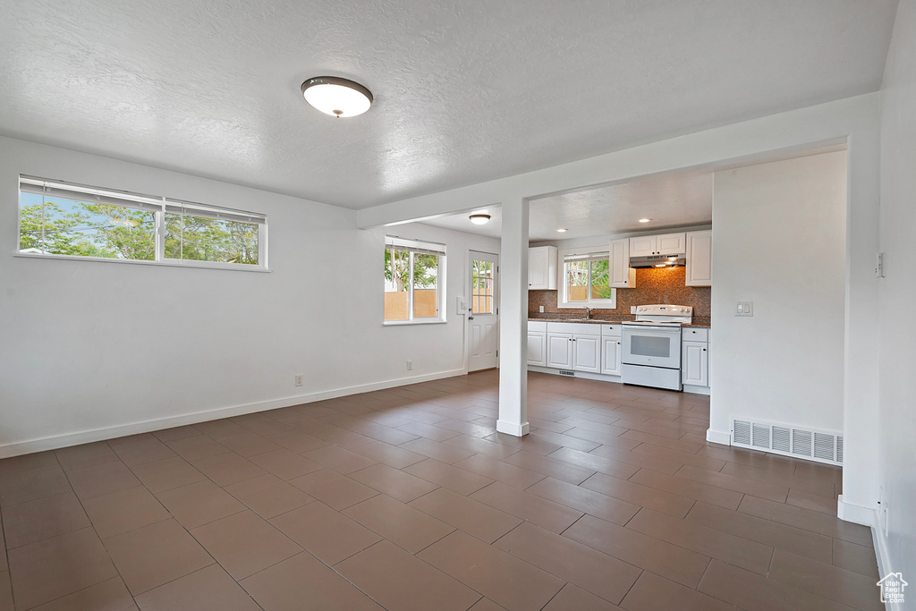 Unfurnished living room with sink, dark tile flooring, and a textured ceiling