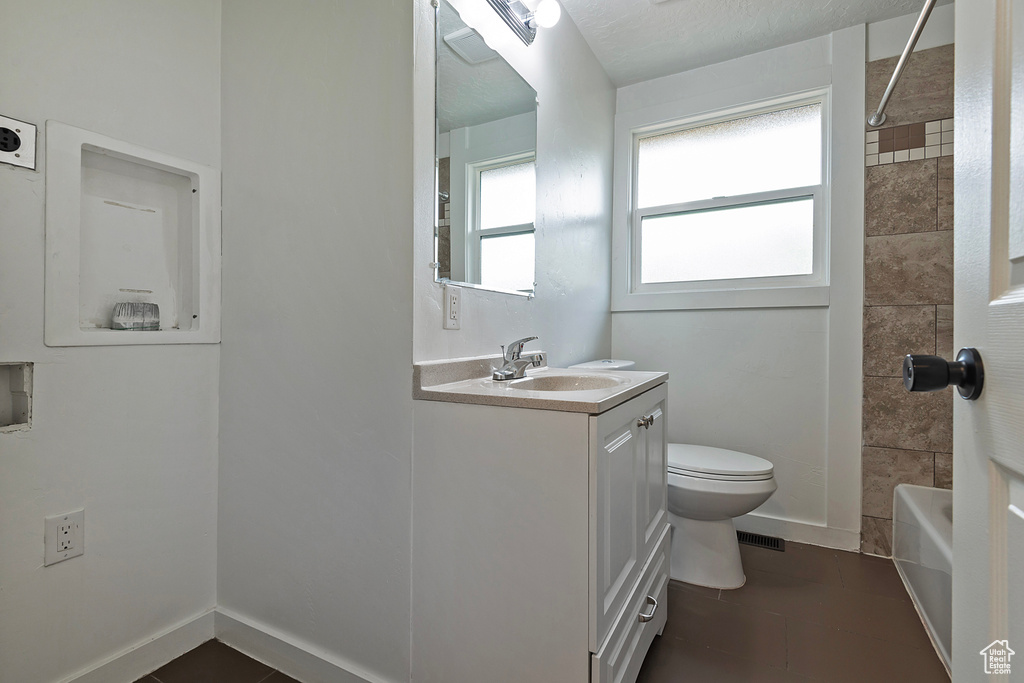 Full bathroom featuring tiled shower / bath, toilet, tile floors, and large vanity