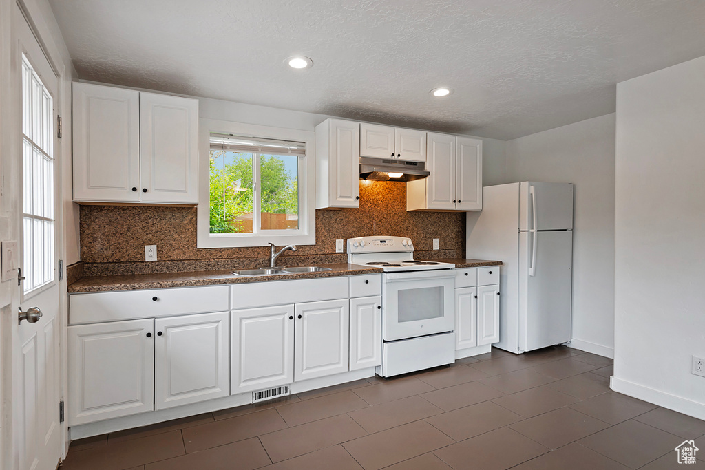 Kitchen with white appliances, sink, tasteful backsplash, and white cabinetry