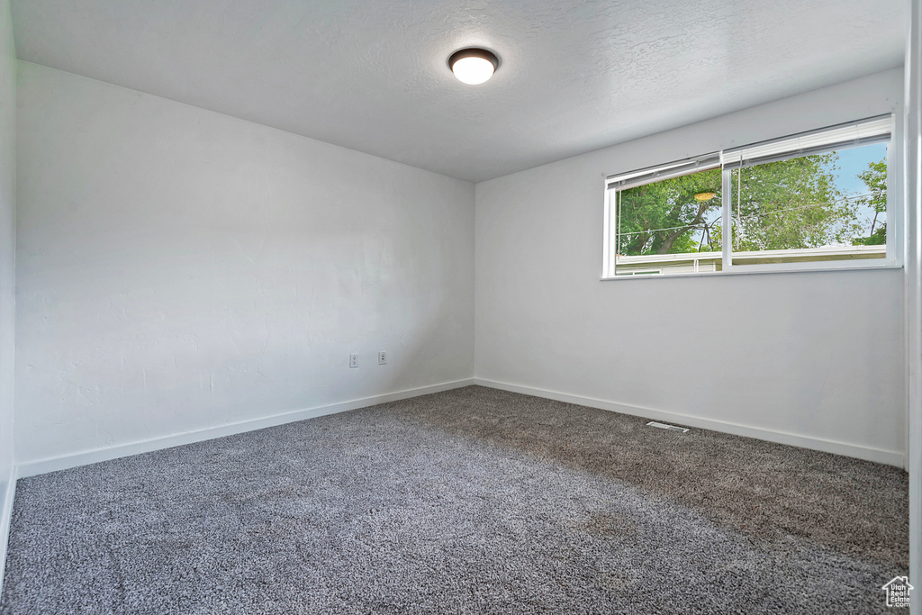 Empty room with a textured ceiling and carpet