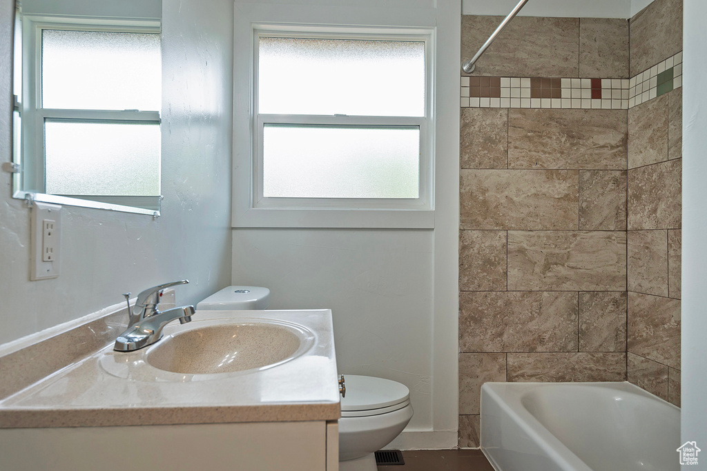 Full bathroom with tiled shower / bath, vanity, and toilet