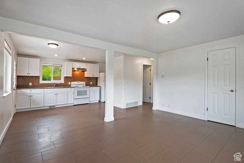 Kitchen featuring white cabinetry, white appliances, backsplash, sink, and dark tile flooring