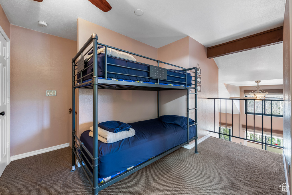 Carpeted bedroom with beamed ceiling and ceiling fan