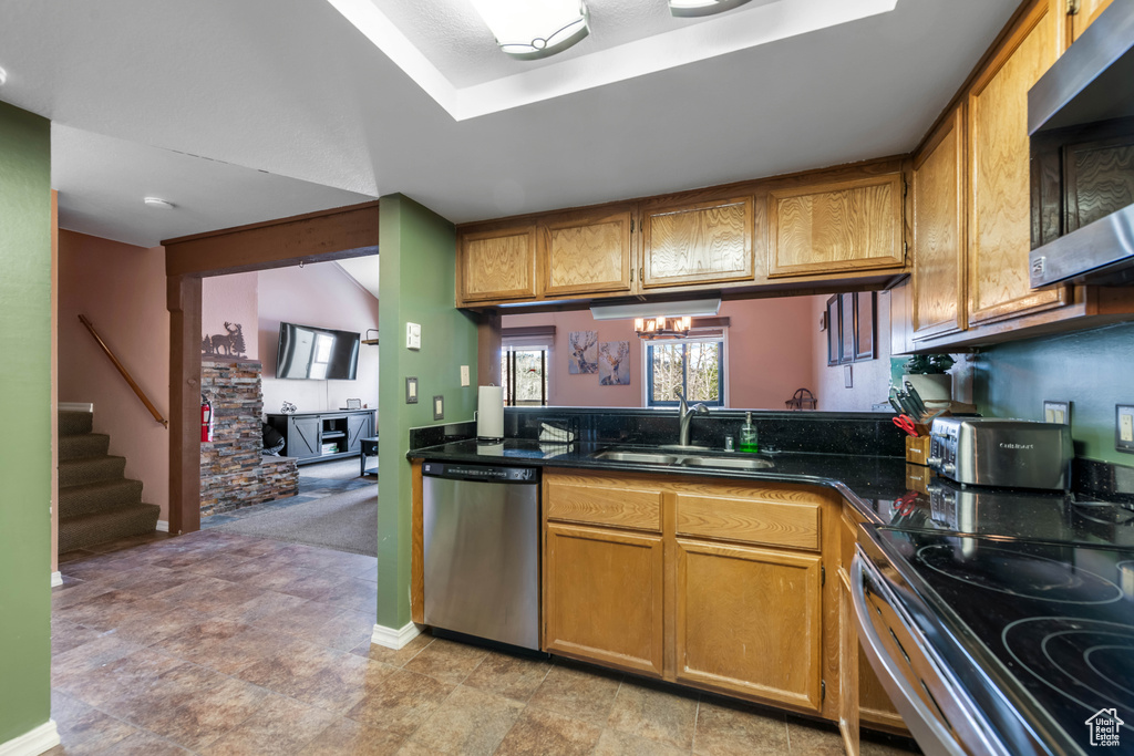 Kitchen featuring appliances with stainless steel finishes, sink, light tile floors, and an inviting chandelier