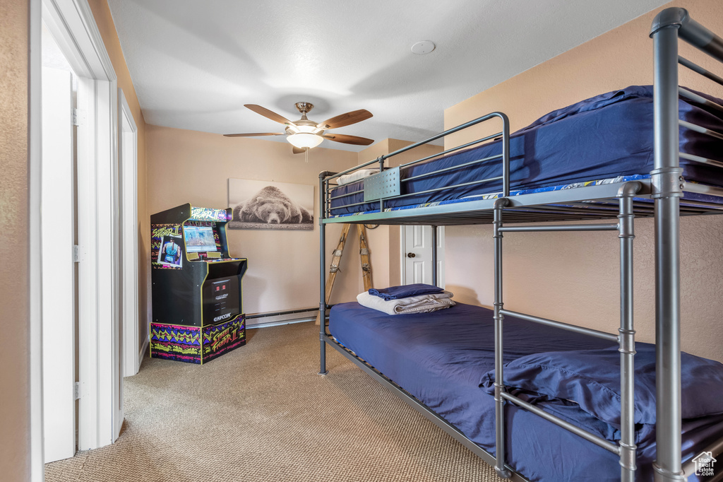 Carpeted bedroom featuring a baseboard heating unit and ceiling fan