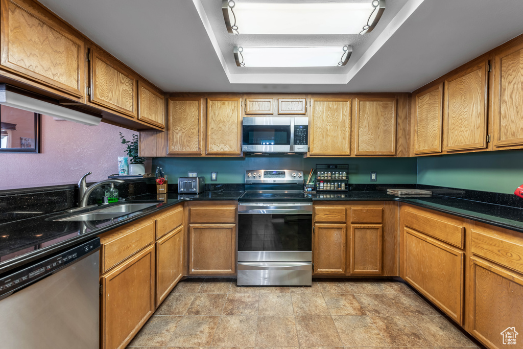 Kitchen featuring appliances with stainless steel finishes, sink, and light tile floors