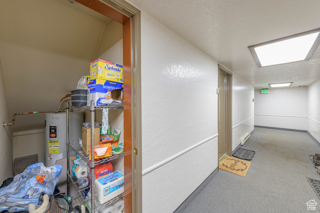 Interior space with a textured ceiling, water heater, and carpet floors