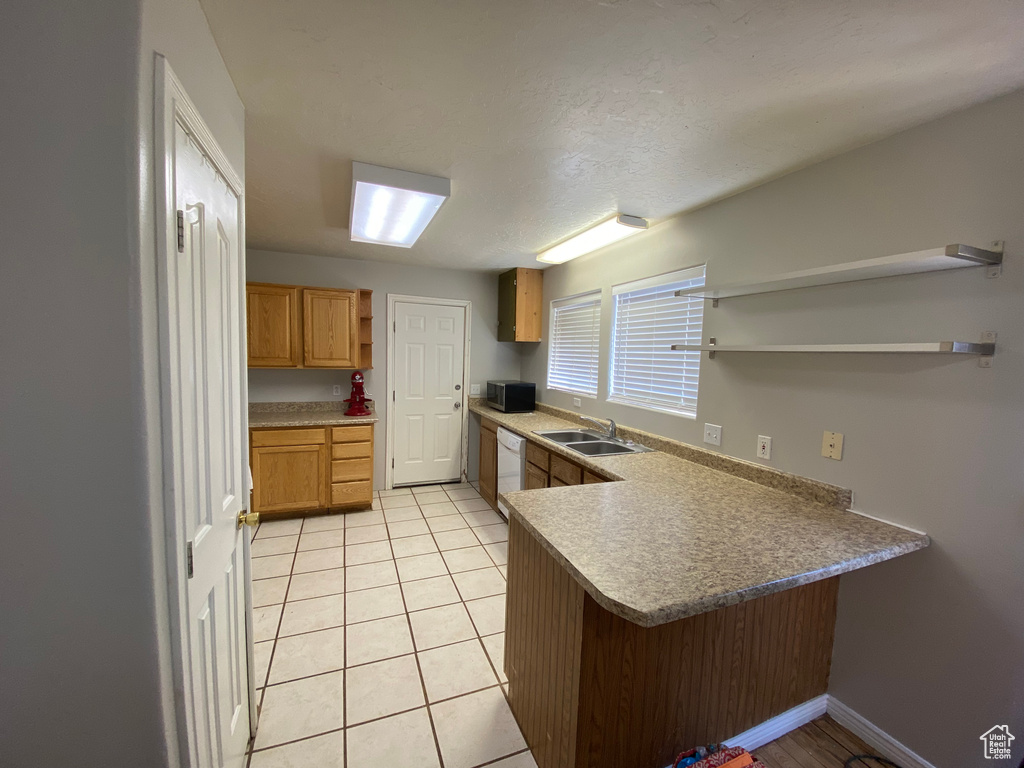 Kitchen featuring sink, kitchen peninsula, white dishwasher, and light tile floors