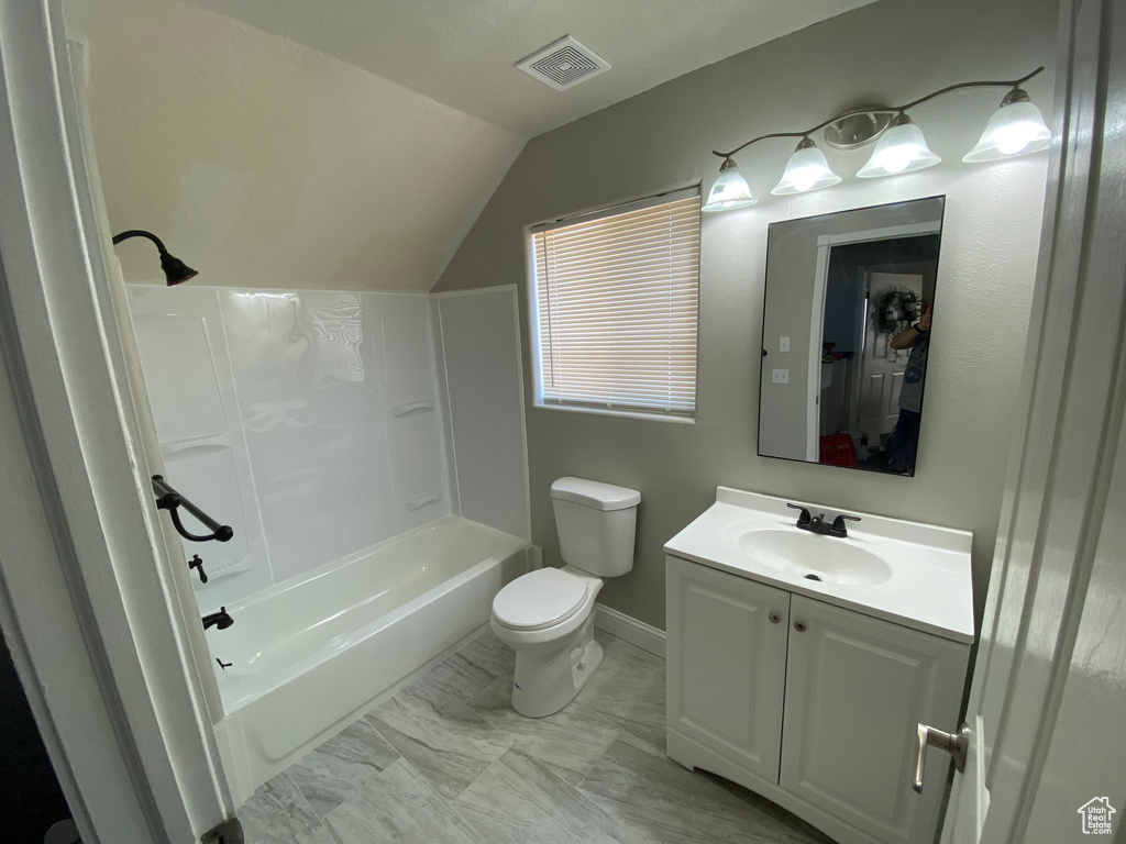 Full bathroom with tub / shower combination, vanity with extensive cabinet space, tile floors, lofted ceiling, and toilet