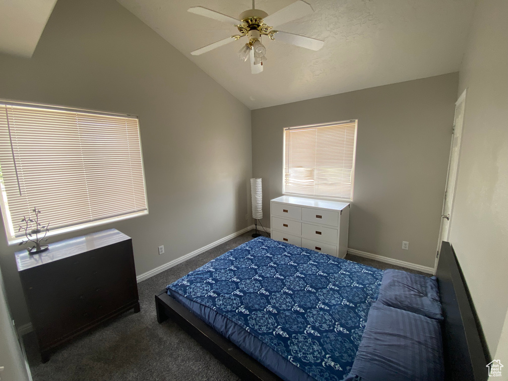 Carpeted bedroom featuring vaulted ceiling and ceiling fan