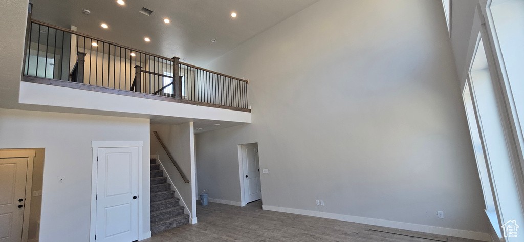 Unfurnished living room with hardwood / wood-style floors and a towering ceiling