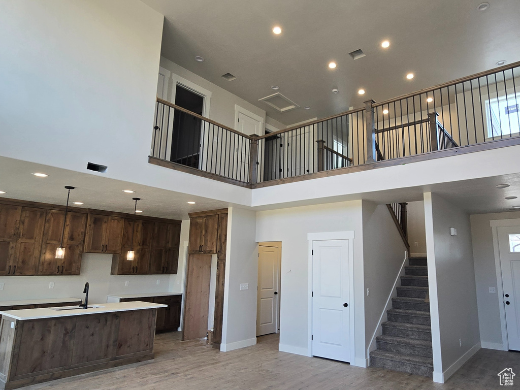 Kitchen featuring sink, dark brown cabinetry, a center island with sink, and a high ceiling