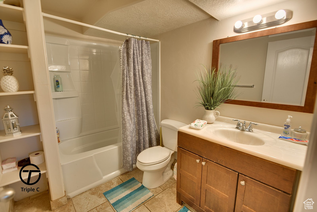 Full bathroom with tile flooring, a textured ceiling, shower / bathtub combination with curtain, toilet, and large vanity