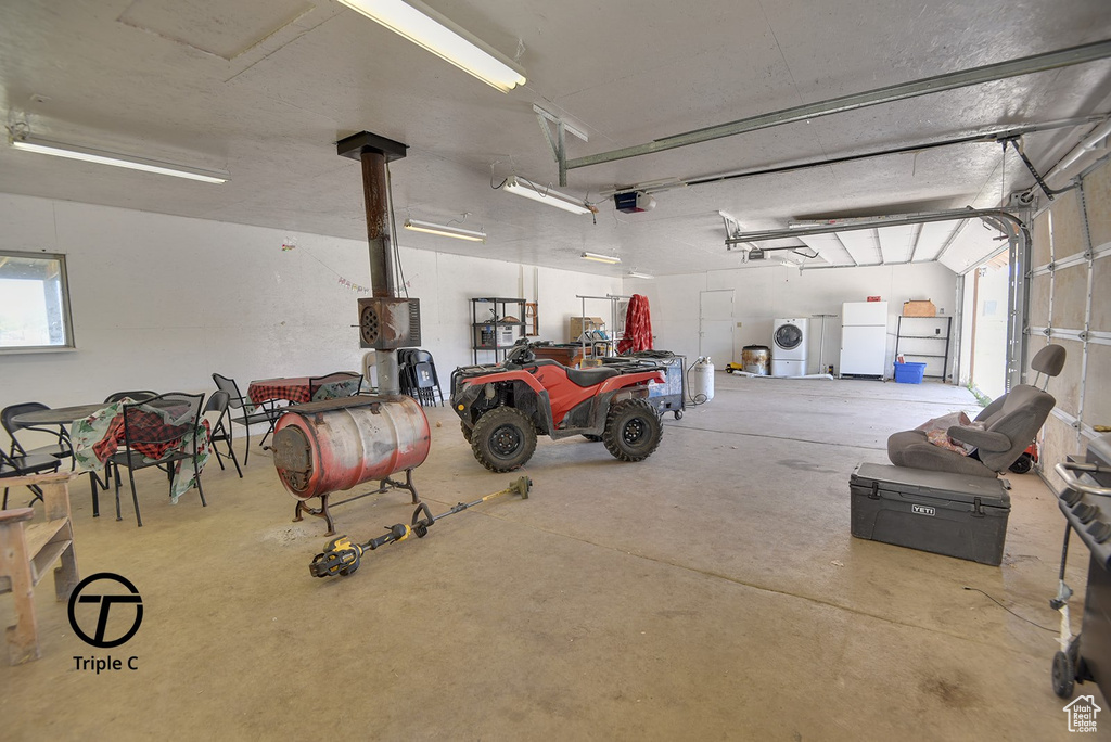 Garage featuring washer / clothes dryer, white refrigerator, and a garage door opener