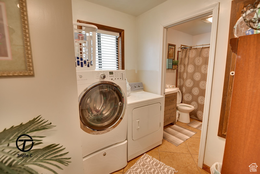 Laundry area with light tile flooring and washer and clothes dryer