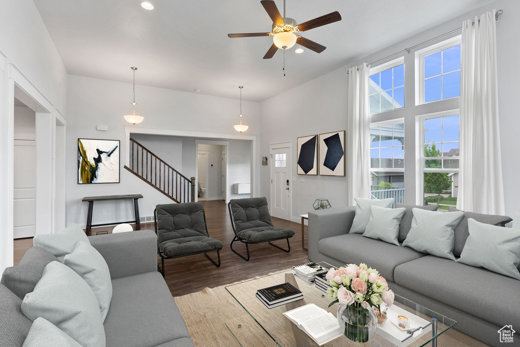 Living room with a towering ceiling, ceiling fan, and hardwood / wood-style floors