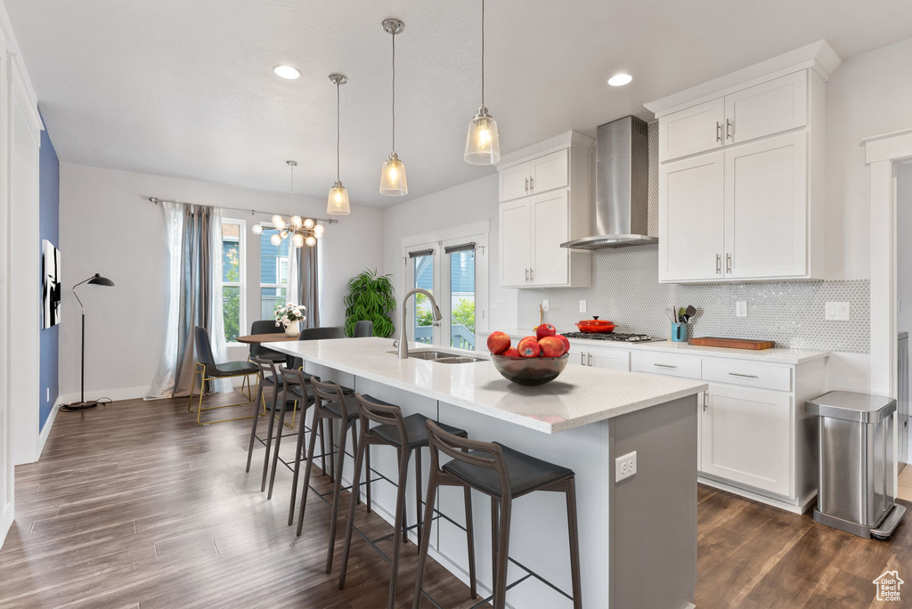 Kitchen featuring an island with sink, wall chimney range hood, tasteful backsplash, and dark hardwood / wood-style floors