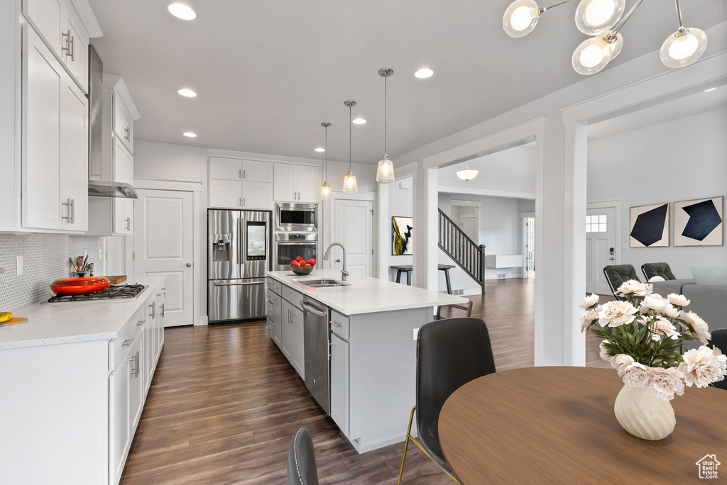 Kitchen featuring appliances with stainless steel finishes, an island with sink, tasteful backsplash, and dark hardwood / wood-style floors