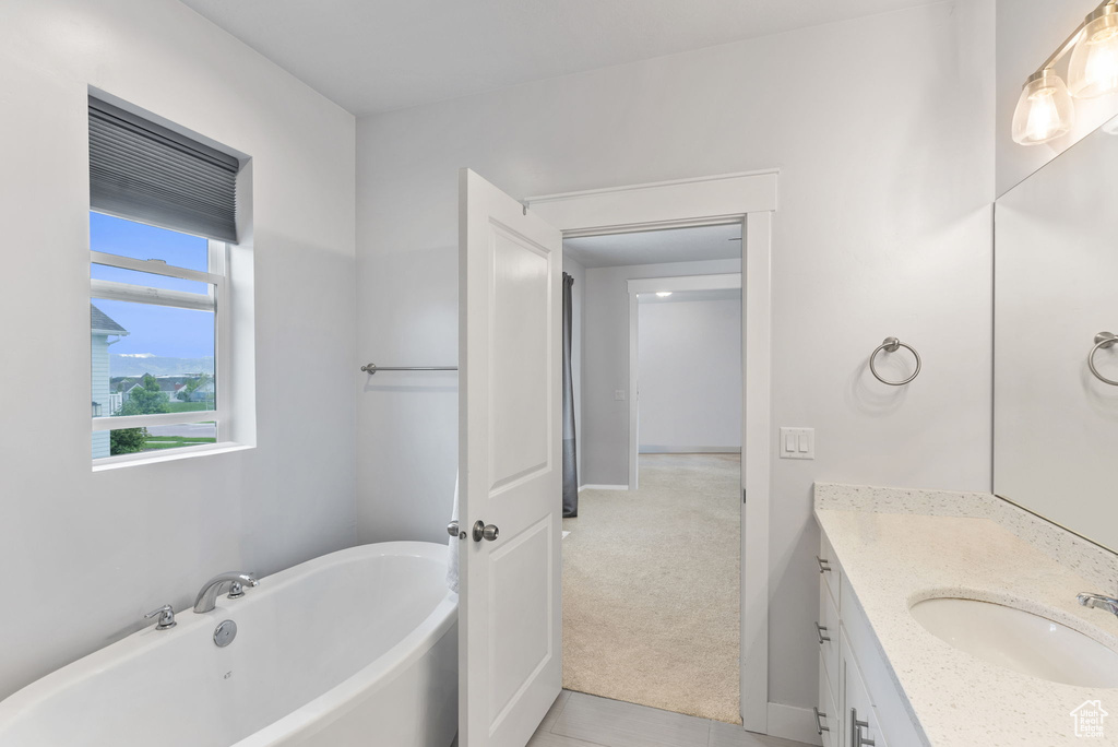 Bathroom with a bath to relax in, vanity with extensive cabinet space, and tile flooring