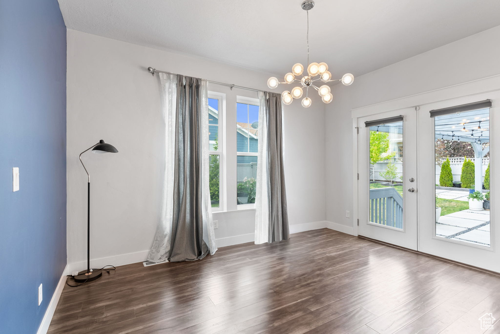 Unfurnished room featuring a notable chandelier, dark hardwood / wood-style flooring, and french doors