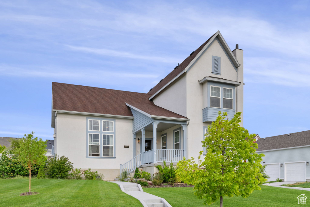 View of front facade featuring a garage, a front lawn, and covered porch