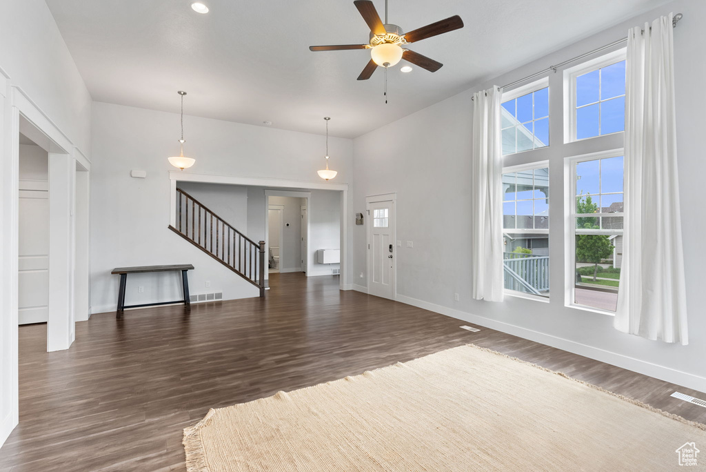 Unfurnished living room with a high ceiling, ceiling fan, and dark hardwood / wood-style flooring