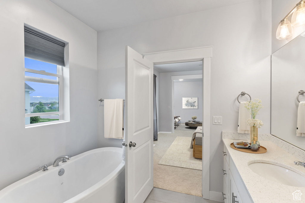 Bathroom featuring a washtub, vanity, and tile floors