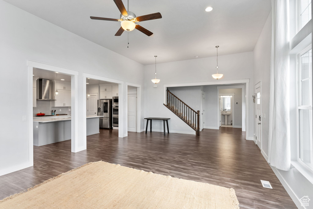 Interior space with a towering ceiling, dark wood-type flooring, and ceiling fan