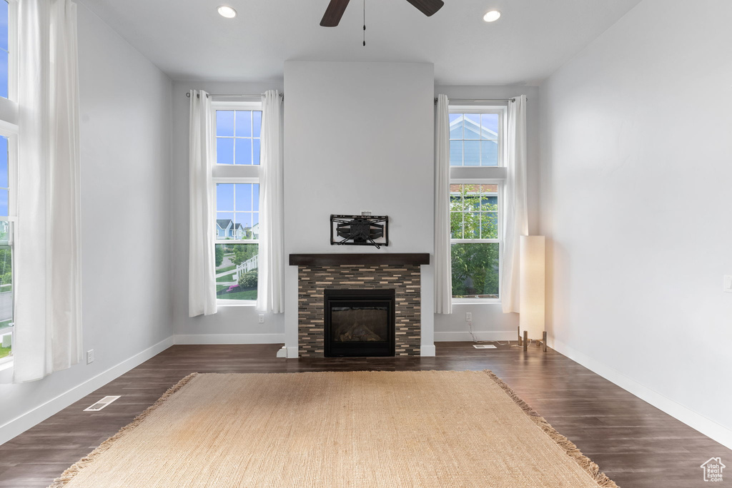 Unfurnished living room featuring ceiling fan, dark hardwood / wood-style floors, and a fireplace