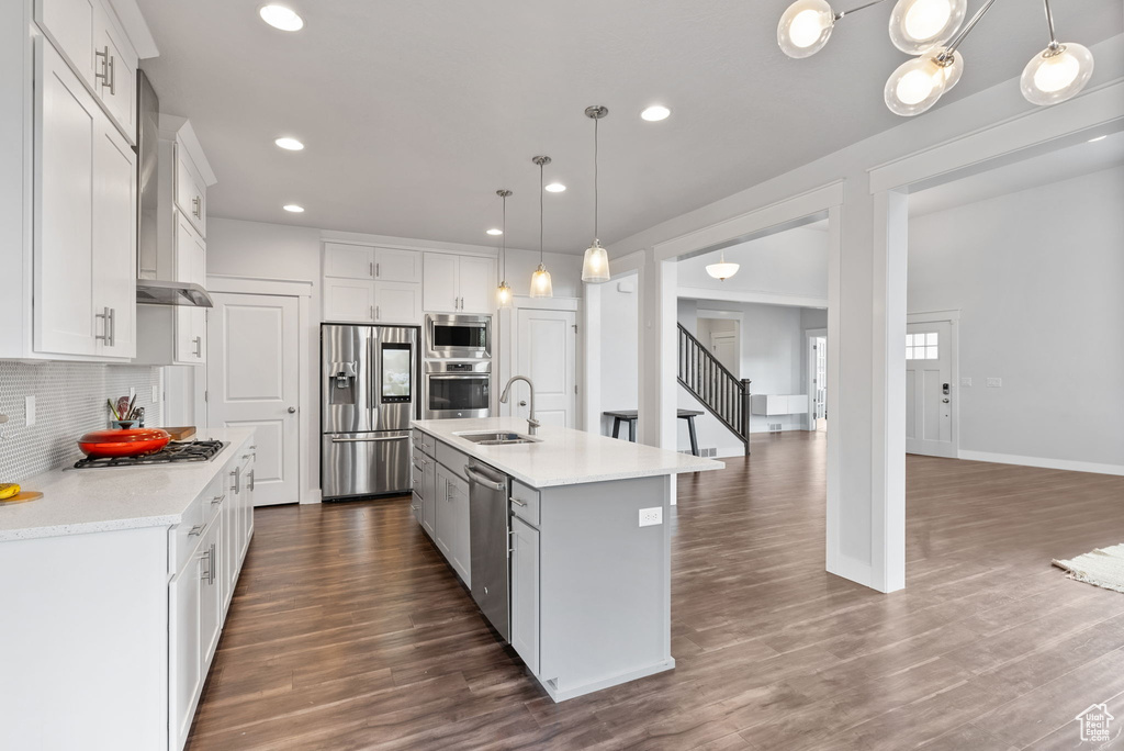 Kitchen featuring stainless steel appliances, dark hardwood / wood-style flooring, a center island with sink, and backsplash