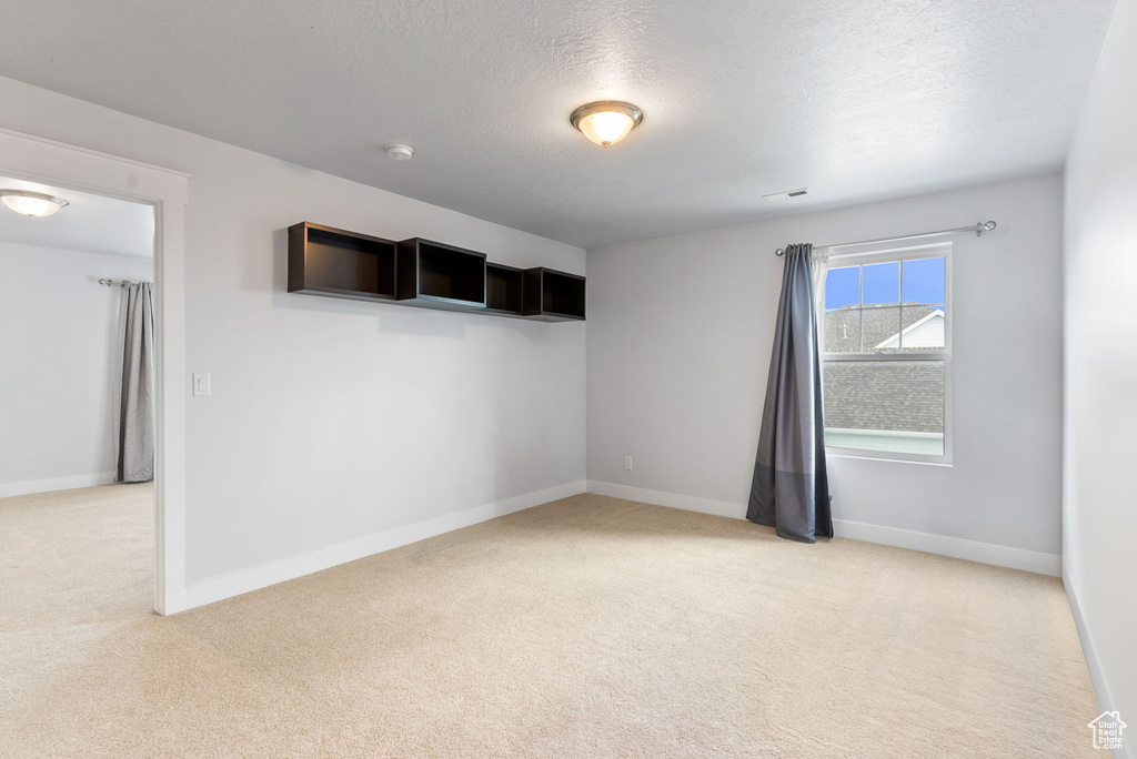 Carpeted spare room with a textured ceiling