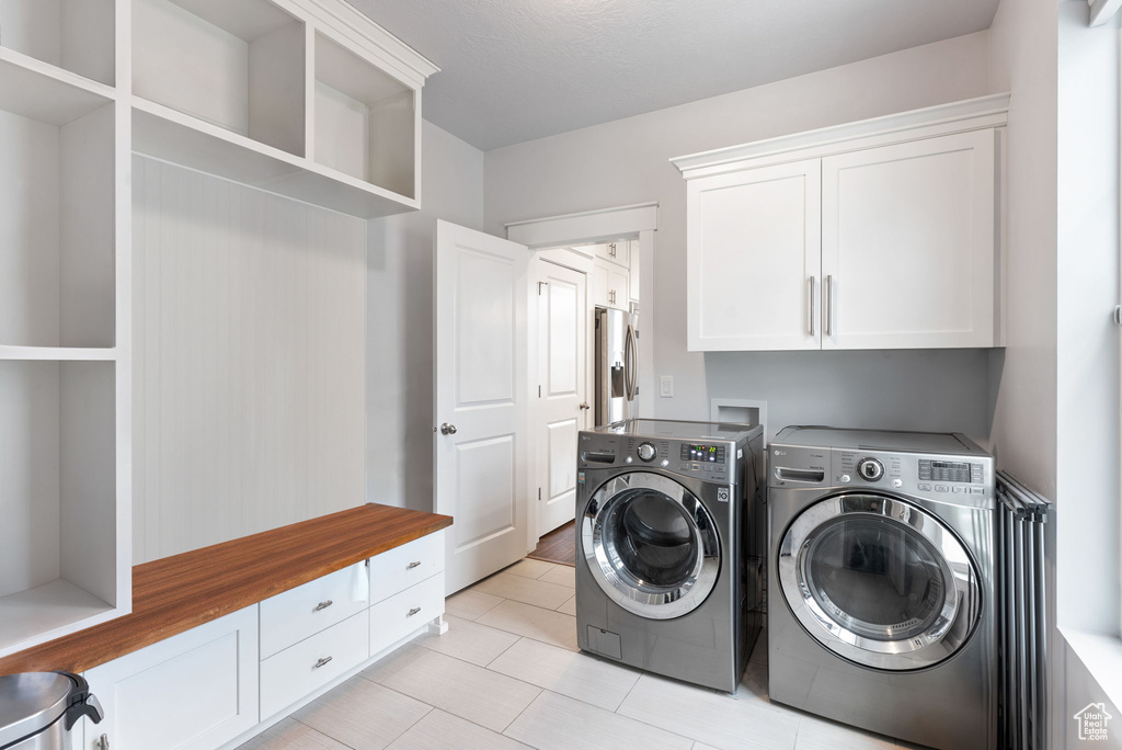 Washroom with washer and dryer, cabinets, light tile floors, and hookup for a washing machine