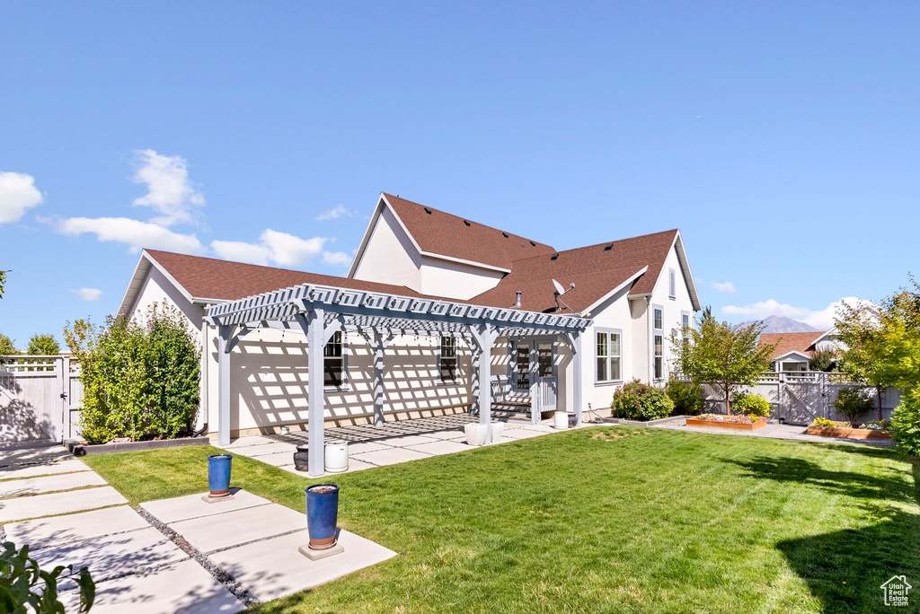 Back of property featuring a lawn, a patio, and a pergola