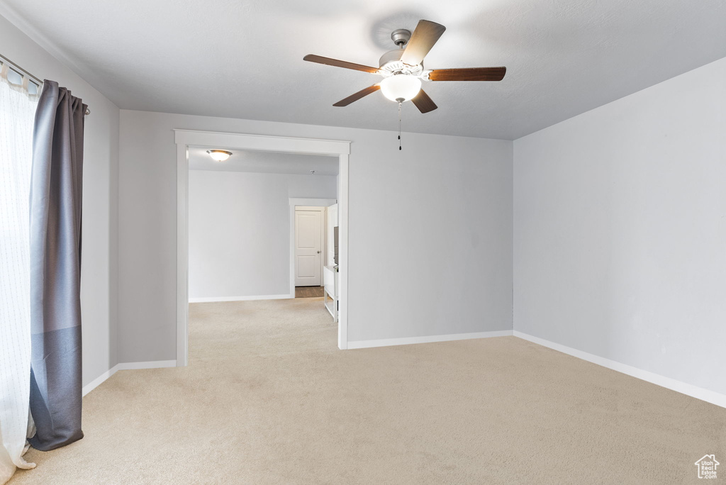 Spare room featuring light carpet and ceiling fan