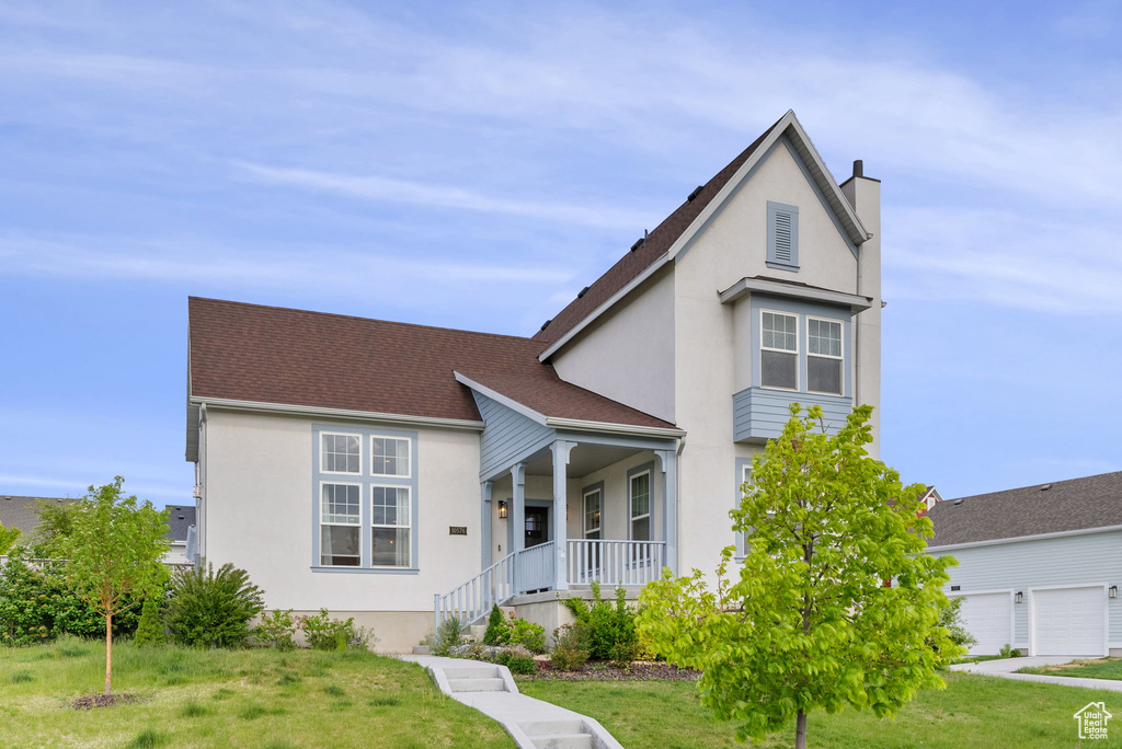 View of front of home featuring a garage, a front lawn, and covered porch