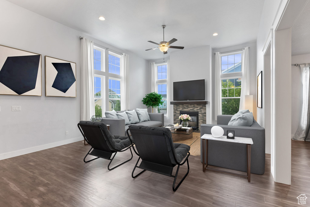 Living room featuring dark hardwood / wood-style flooring, a stone fireplace, and ceiling fan