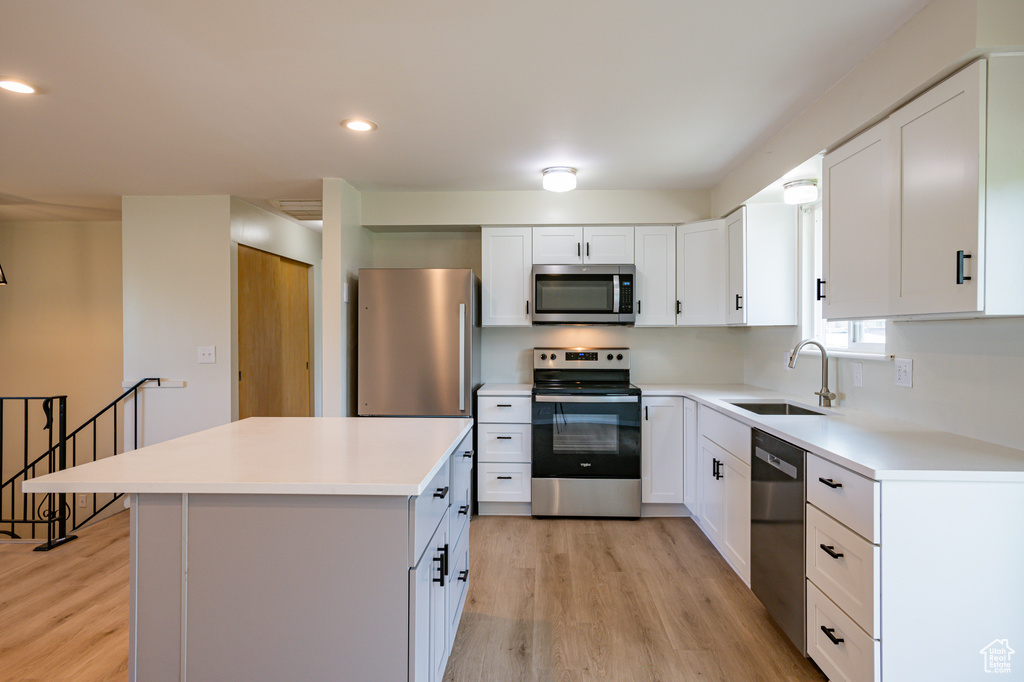 Kitchen featuring appliances with stainless steel finishes, sink, light hardwood / wood-style floors, and a kitchen island