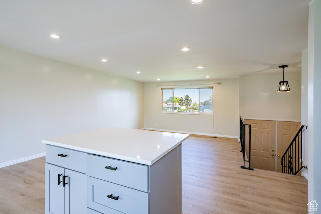 Kitchen with a center island, light hardwood / wood-style floors, white cabinetry, and pendant lighting