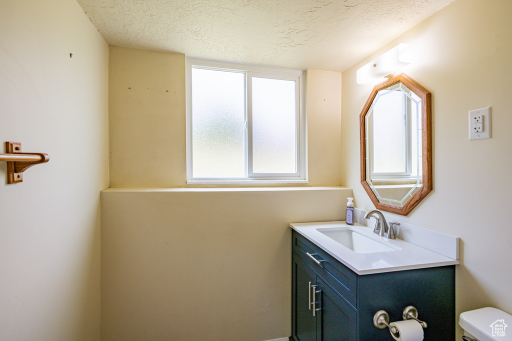 Bathroom with a textured ceiling, toilet, and vanity