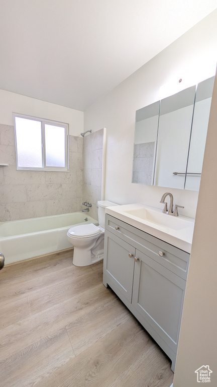 Full bathroom featuring vanity, toilet, tiled shower / bath combo, and hardwood / wood-style floors